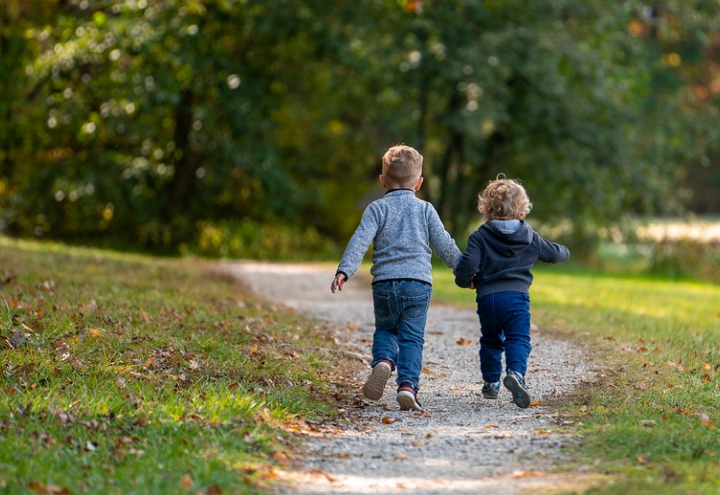 Dzieci w parku biegną szczęśliwie po ścieżce